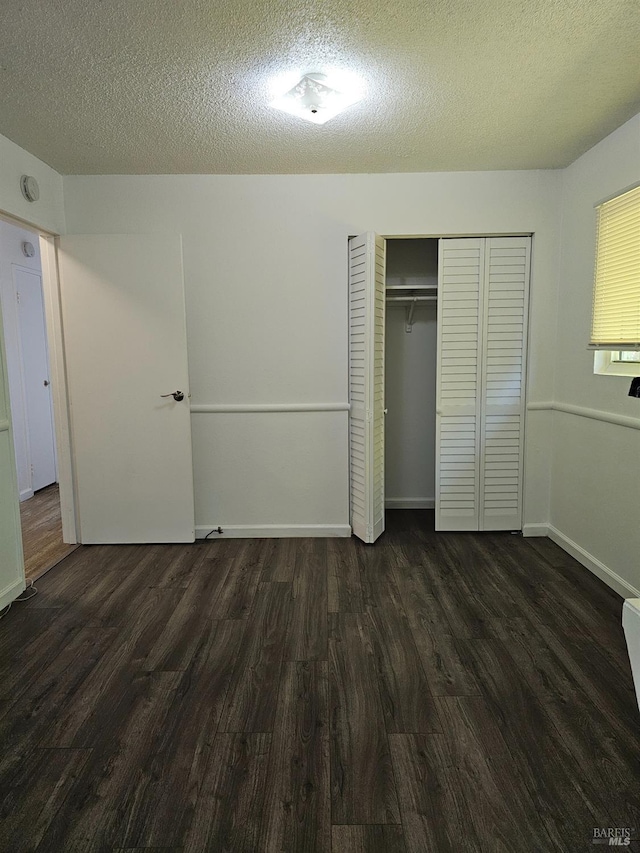 unfurnished bedroom with a textured ceiling and dark hardwood / wood-style flooring