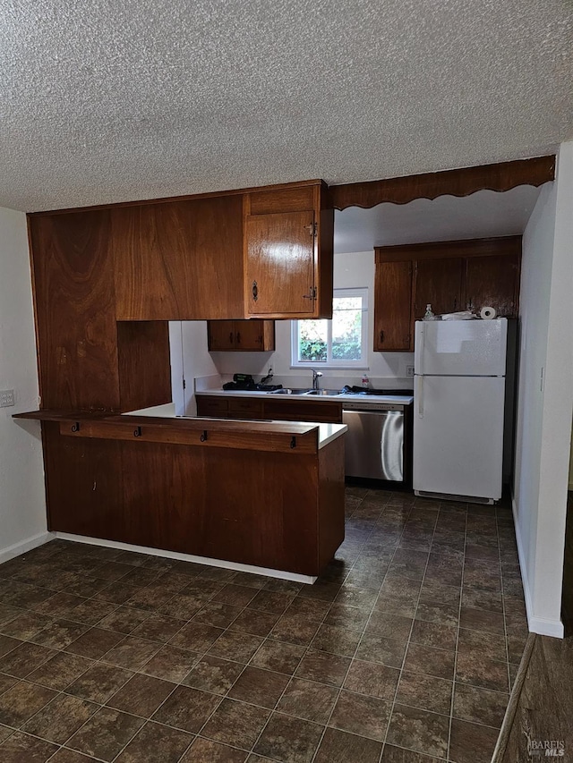 kitchen with stainless steel dishwasher, white refrigerator, kitchen peninsula, and a textured ceiling