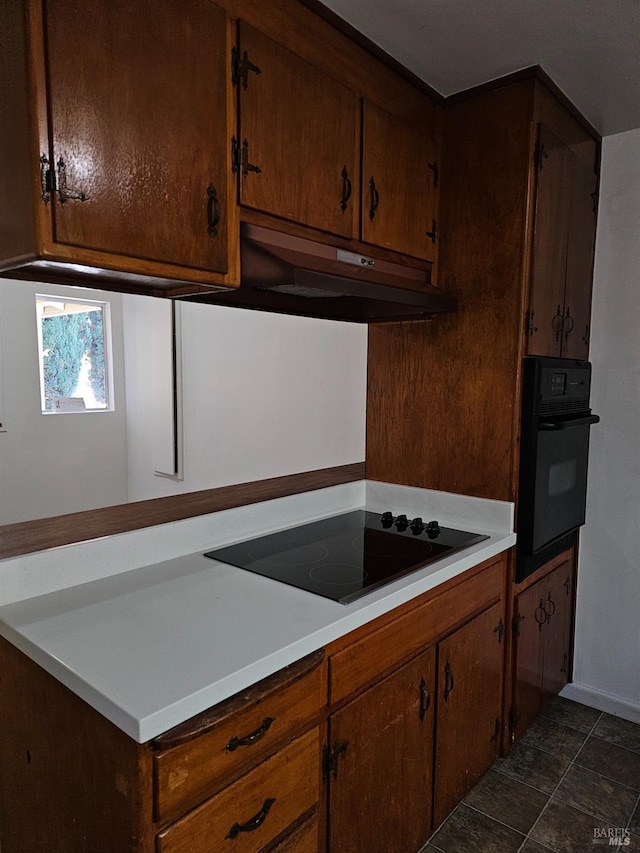 kitchen with black appliances and dark tile patterned flooring