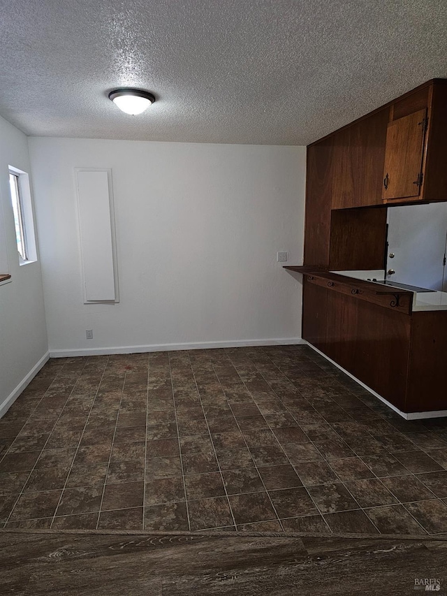 kitchen with dark brown cabinets, white fridge, and a textured ceiling