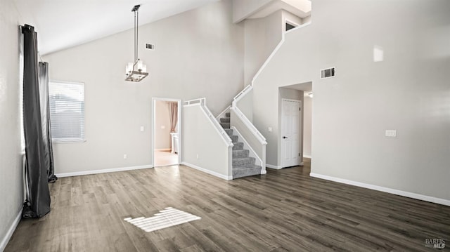 unfurnished living room featuring dark hardwood / wood-style flooring, high vaulted ceiling, and an inviting chandelier