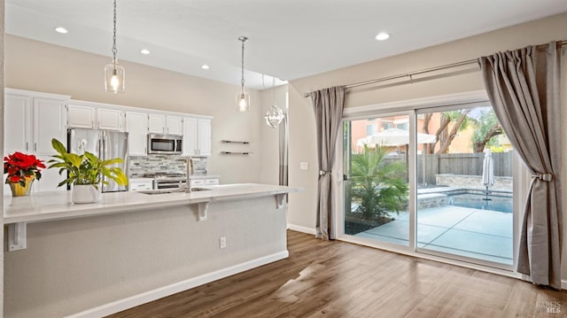 kitchen featuring tasteful backsplash, stainless steel appliances, pendant lighting, white cabinets, and dark hardwood / wood-style floors