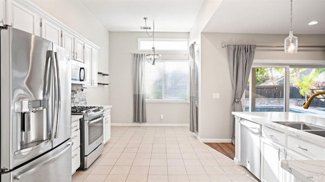 kitchen with light countertops, tasteful backsplash, stainless steel appliances, pendant lighting, and white cabinets