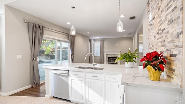 kitchen featuring dishwasher, a stone fireplace, sink, light hardwood / wood-style floors, and white cabinetry