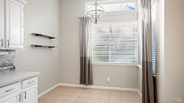 interior space with white cabinetry, plenty of natural light, light tile patterned floors, and a chandelier