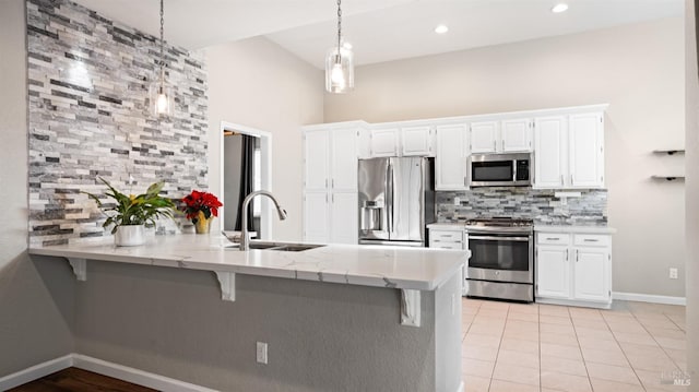 kitchen with kitchen peninsula, appliances with stainless steel finishes, sink, white cabinetry, and a breakfast bar area