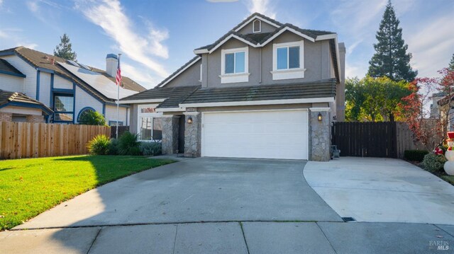view of front facade featuring stone siding, driveway, fence, and an attached garage