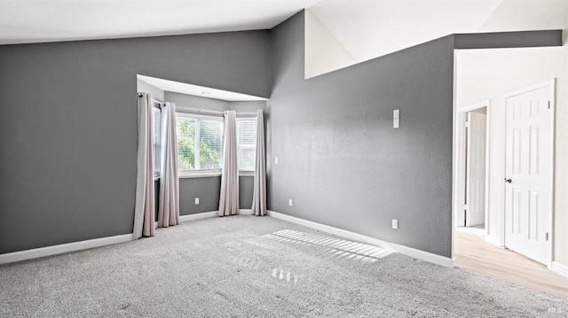 carpeted spare room with baseboards and high vaulted ceiling