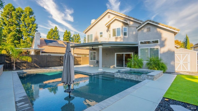 back of house with a patio, a storage unit, and a pool with hot tub