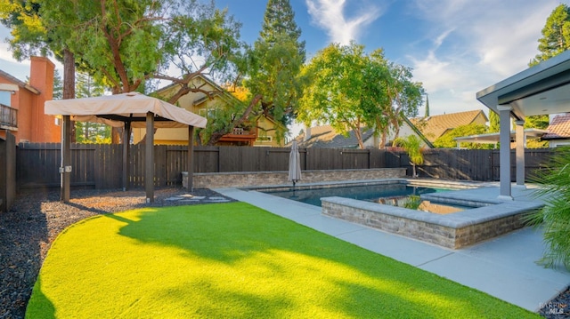 view of swimming pool featuring a jacuzzi and a yard