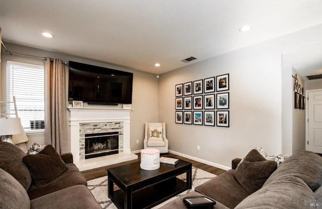 living room with wood-type flooring and a stone fireplace