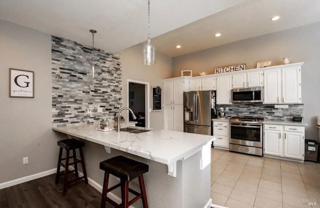 kitchen featuring hanging light fixtures, tasteful backsplash, kitchen peninsula, white cabinets, and appliances with stainless steel finishes