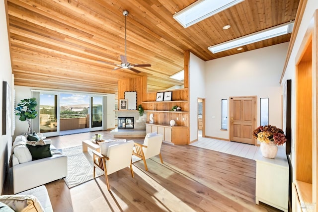 living room featuring a skylight, ceiling fan, high vaulted ceiling, light hardwood / wood-style floors, and wood ceiling