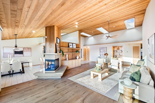 living room featuring a skylight, ceiling fan, built in features, light wood-type flooring, and wood ceiling