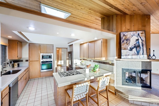 kitchen with sink, wooden ceiling, kitchen peninsula, lofted ceiling with skylight, and appliances with stainless steel finishes