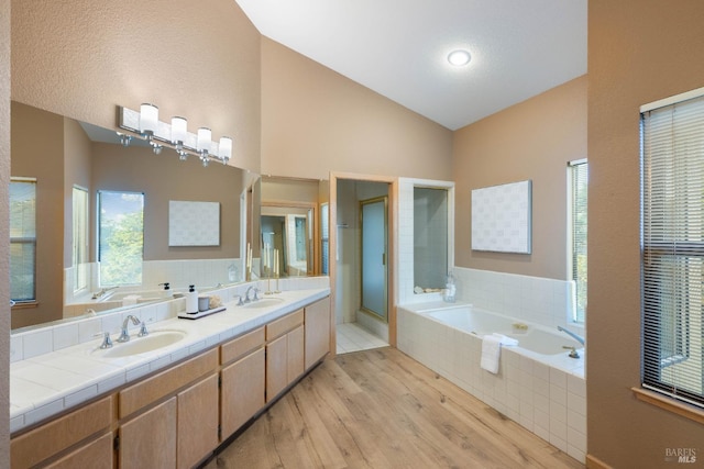 bathroom featuring vanity, separate shower and tub, hardwood / wood-style flooring, and vaulted ceiling