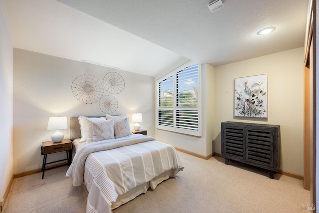 bedroom featuring a textured ceiling, light carpet, and vaulted ceiling