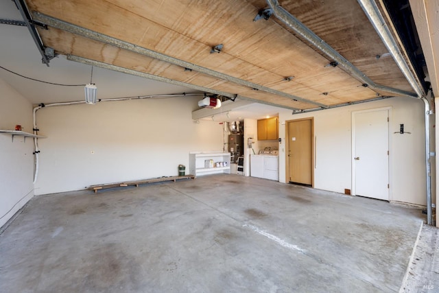 garage featuring washing machine and dryer, strapped water heater, and a garage door opener