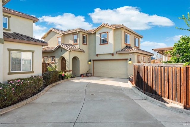 mediterranean / spanish house with a garage, fence, driveway, and a tile roof