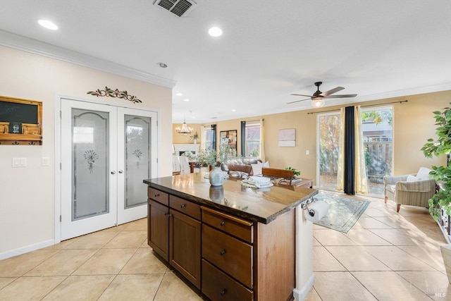 kitchen featuring ceiling fan with notable chandelier, a center island, light tile patterned floors, crown molding, and french doors