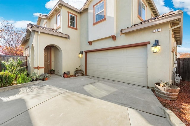 view of front of home featuring fence, stucco siding, an attached garage, driveway, and a tile roof