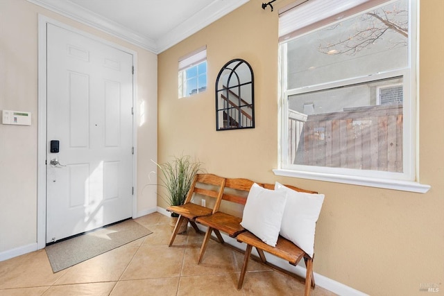 tiled entryway featuring crown molding and baseboards