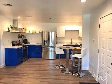 kitchen featuring white cabinetry, hardwood / wood-style flooring, ventilation hood, stainless steel appliances, and blue cabinets