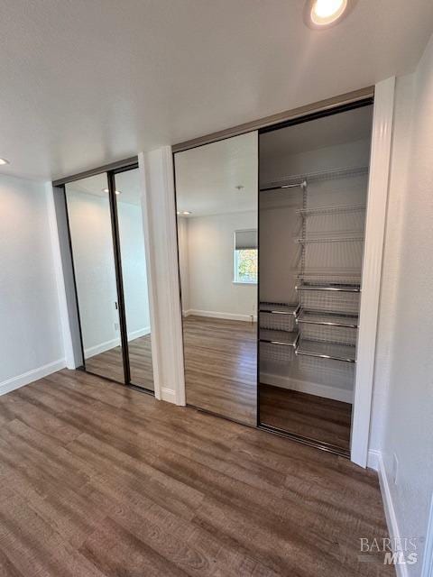 unfurnished bedroom with two closets and hardwood / wood-style flooring