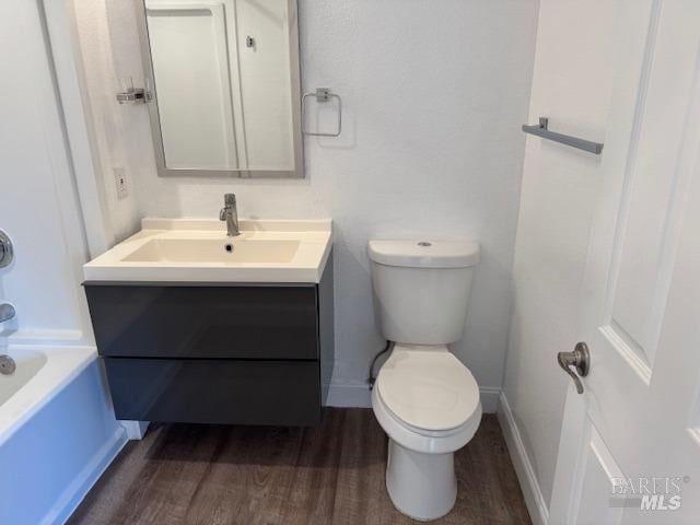 bathroom featuring toilet, vanity, and hardwood / wood-style floors