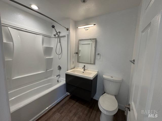 full bathroom featuring a textured ceiling, vanity, toilet, hardwood / wood-style flooring, and bathtub / shower combination