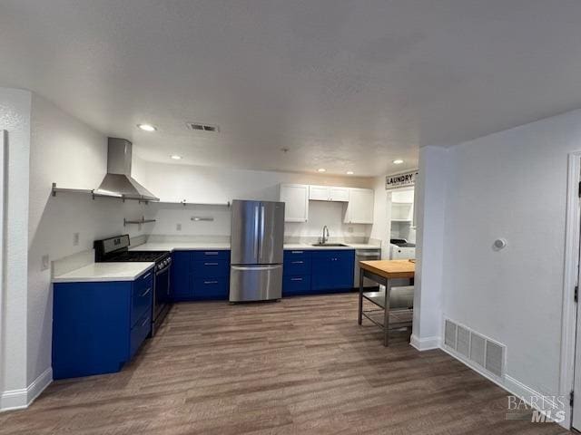 kitchen with white cabinetry, hardwood / wood-style flooring, appliances with stainless steel finishes, wall chimney exhaust hood, and sink