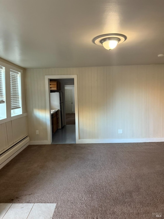 empty room featuring carpet, baseboards, and baseboard heating