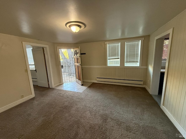 empty room featuring a baseboard heating unit, light colored carpet, and wooden walls