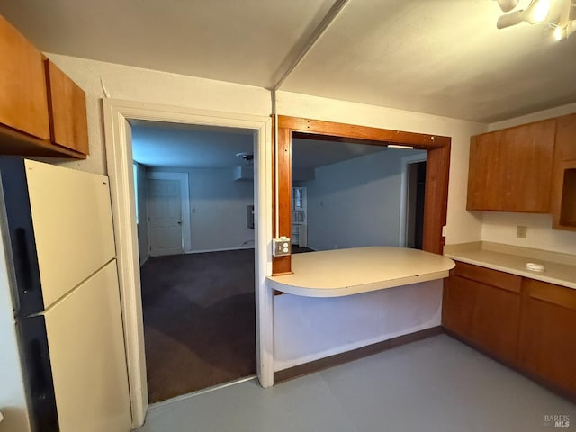 kitchen with light countertops, brown cabinetry, and freestanding refrigerator