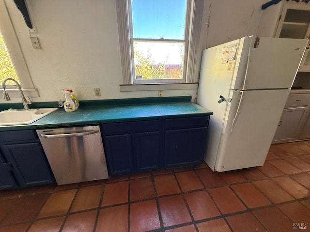 kitchen with freestanding refrigerator, a sink, dark countertops, and stainless steel dishwasher