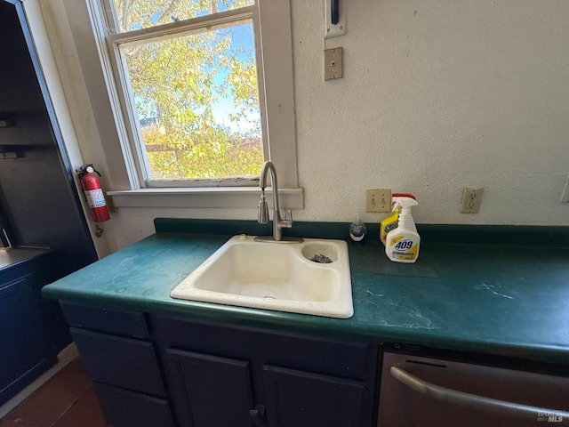 kitchen with dishwasher, a textured wall, and a sink