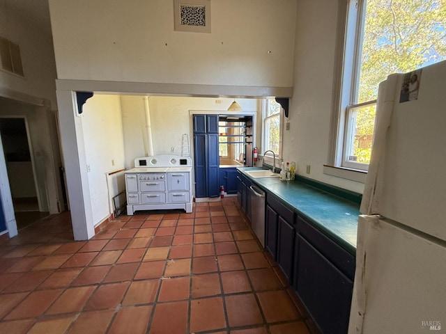 kitchen featuring range, tile patterned floors, a sink, freestanding refrigerator, and stainless steel dishwasher