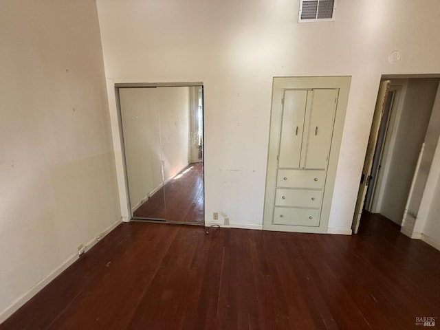 interior space with a closet, visible vents, baseboards, and wood finished floors