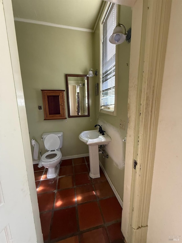 bathroom featuring toilet, ornamental molding, a sink, baseboards, and tile patterned floors