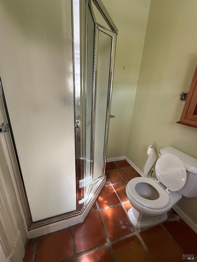 bathroom featuring a stall shower, tile patterned flooring, toilet, and baseboards