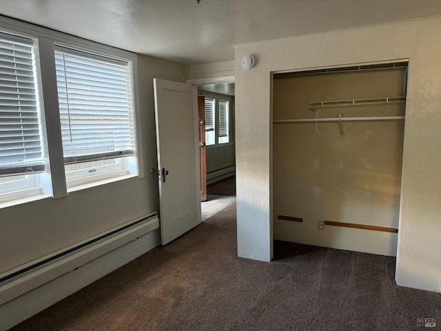 unfurnished bedroom featuring a baseboard heating unit, carpet, and a closet