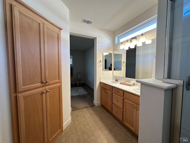 bathroom with tile patterned flooring, vanity, and a textured ceiling