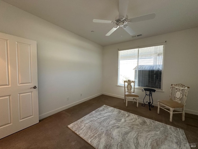 living area featuring dark carpet and ceiling fan