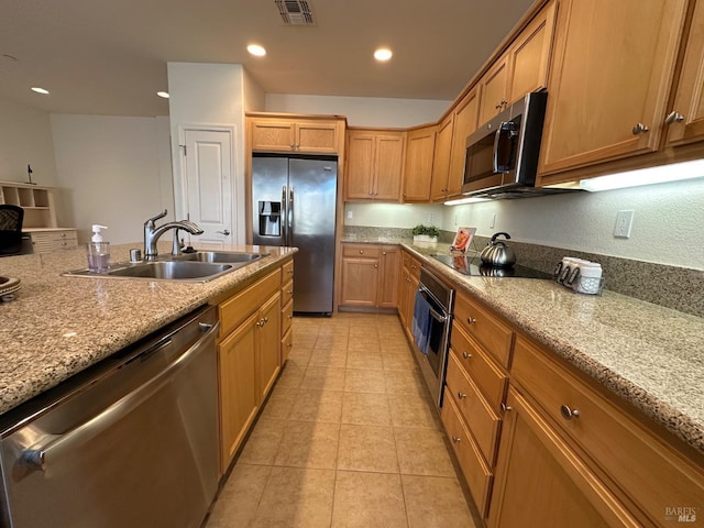 kitchen with light stone countertops, light tile patterned floors, stainless steel appliances, and sink