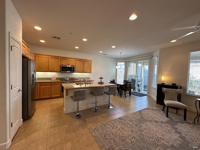 kitchen with sink, a kitchen breakfast bar, light stone counters, a kitchen island with sink, and appliances with stainless steel finishes