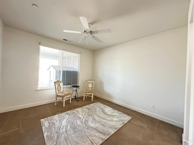 sitting room with ceiling fan and dark colored carpet