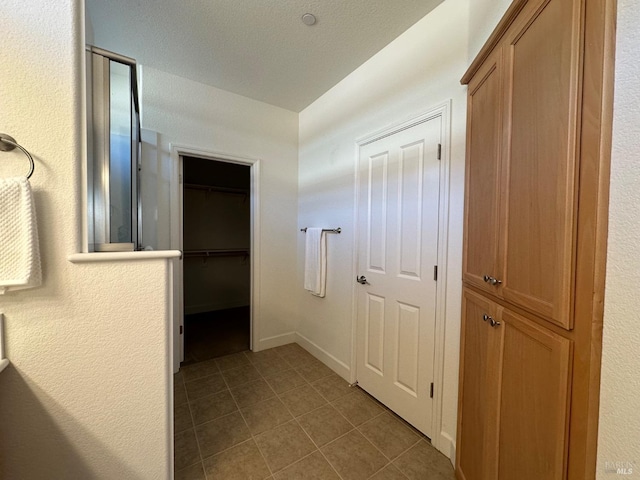 hallway with light tile patterned floors and a textured ceiling