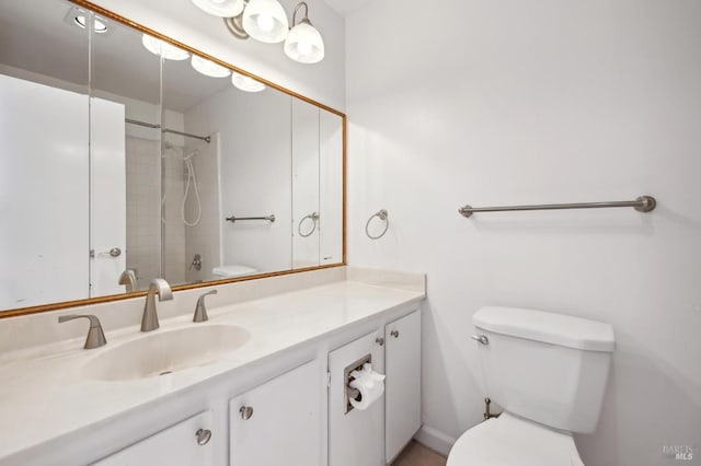 bathroom with a tile shower, vanity, and toilet