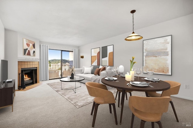 dining room featuring light colored carpet and a tiled fireplace