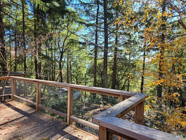 wooden terrace featuring a wooded view